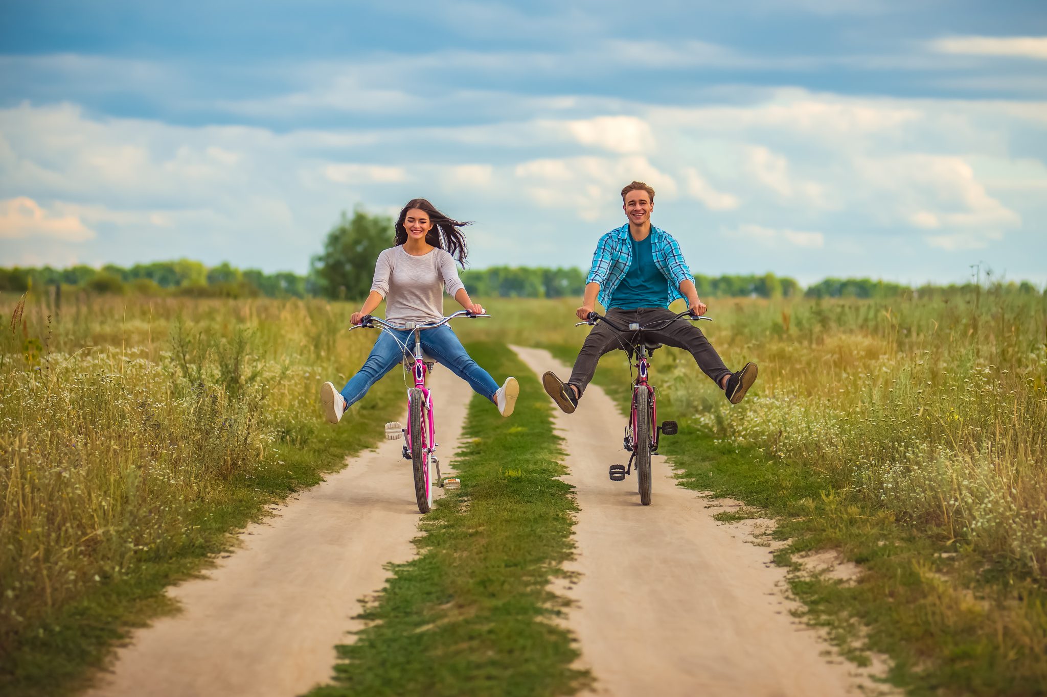 The happy couple ride a bicycle in a field
