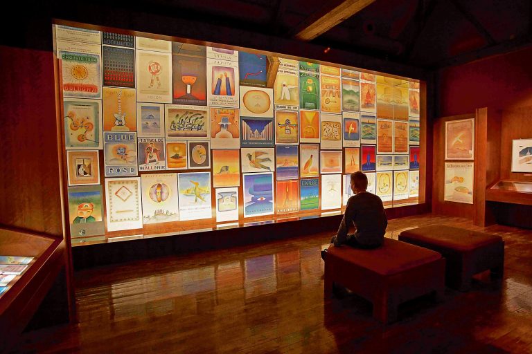 Homme devant le mur d'affiches de la Fondation Folon