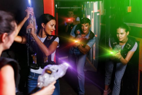 Portrait of active young friends standing with laser guns during laser tag game in dark room Portrait of active young friends standing with laser guns during laser tag game in dark room