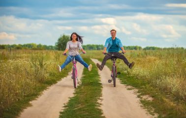 The happy couple ride a bicycle in a field