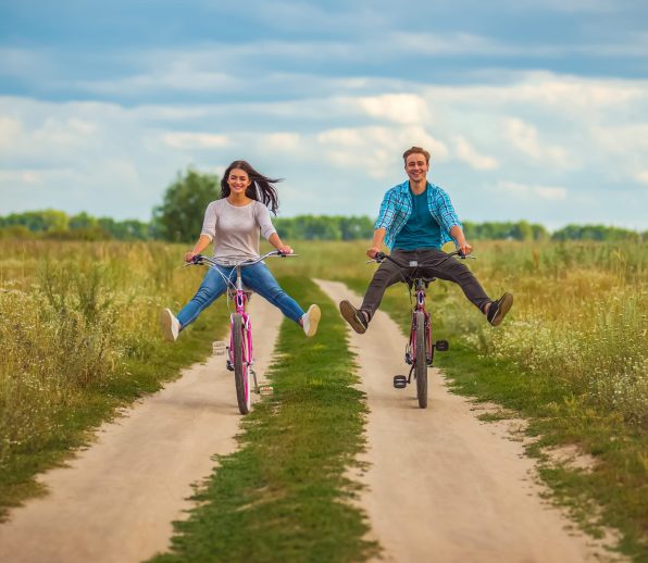 The happy couple ride a bicycle in a field The happy couple ride a bicycle in a field