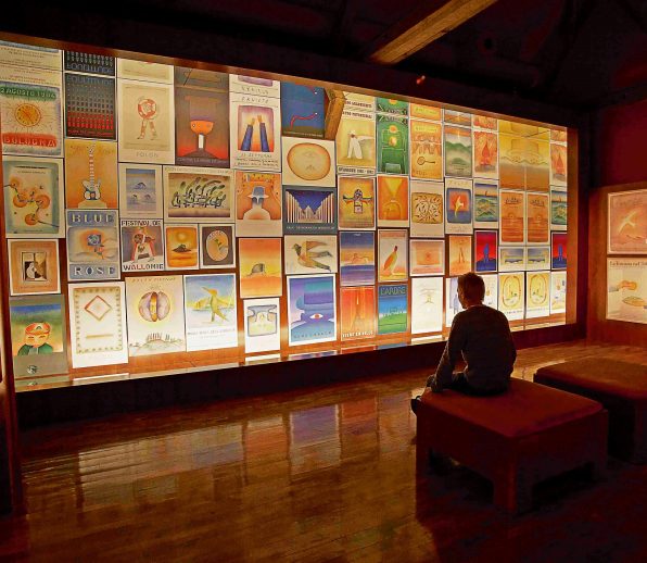 Homme devant le mur d'affiches de la Fondation Folon